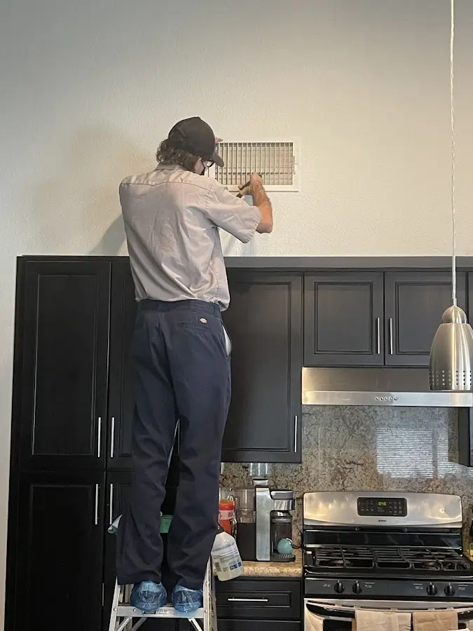Technician inspecting an air vent during HVAC service in Fort Belvoir